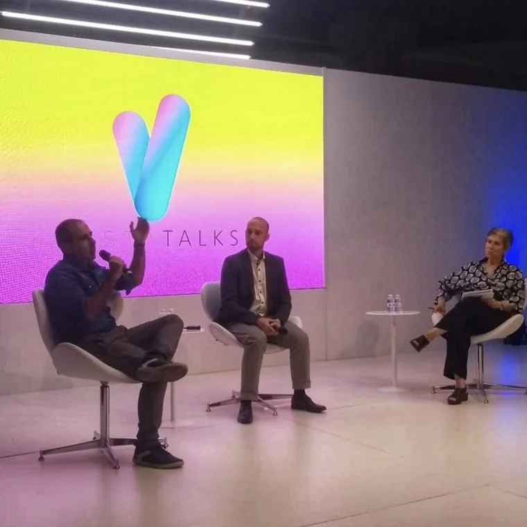 Roberto Calderon de microfone em painel com Rafael Kiso, diante de uma plateia de lojistas